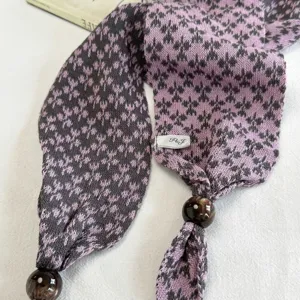 Knitted long scarf detail view, purple snowflake pattern with wooden beads decoration.