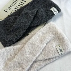 Detailed view of soft knitted winter headbands in dark grey and beige with cute brand tags.