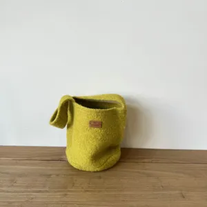 Detailed close-up view of the yellow-green felt bucket bag showing texture and leather label.