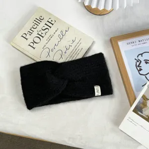 Detailed view of a soft black knitted cross headband, perfect for autumn and winter warmth.
