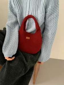 Detail view of a cozy red knit handbag with fuzzy plush texture and cute handle design.