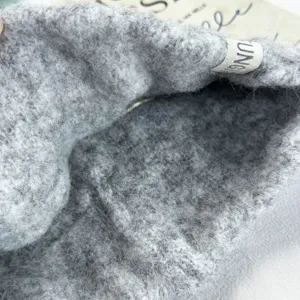 Vue détaillée du bandeau tricoté épais et duveteux en gris, avec texture douce et petite étiquette.