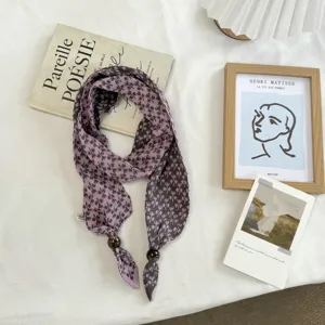 Close-up of purple snowflake knit scarf with wooden beads, cozy retro autumn neck accessory.
