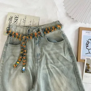 Stijlvolle lichte denim jeans gecombineerd met een kleurrijke tweed kwast riem.