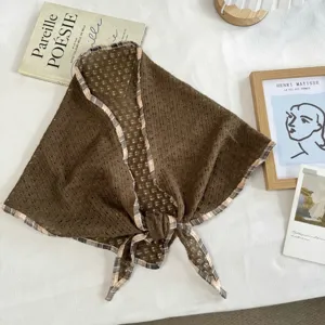 Vista detallada del pañuelo triangular marrón calado con borde a cuadros para un estilo veraniego.