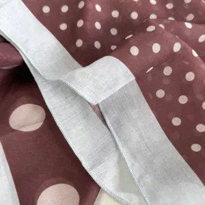 Detalle de tela de panuelo de seda con lunares marrones, accesorio elegante para mujer.