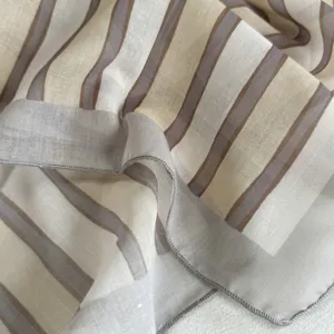 Primer plano detallado de un elegante pañuelo a rayas, tonos neutros refinados y textura suave.
