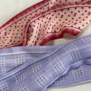 Detailopname van lichte zijden sjaal met roze stippen en paars geruit patroon voor dames.