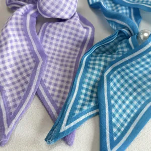 Close-up detail shot of elegant plaid neck ribbons in purple and blue, soft fabric design.