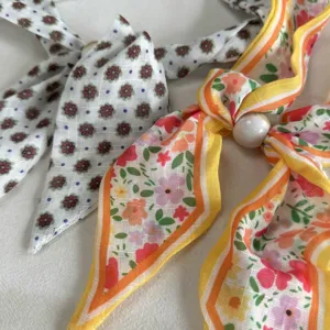 Close-up detail of retro floral fabric scarf necklace with bead accent, elegant women accessory.