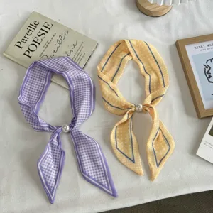 Close-up of narrow long silk scarves with chic plaid and polka dot patterns, pearl accent.