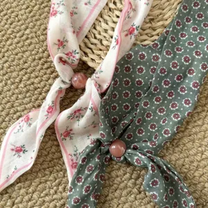 Detailansicht des Retro-Blumen-Seidenschals mit verstellbarer Perle für das Haar.