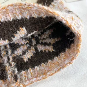 Nahaufnahme des flauschigen Strick-Ohrwärmers mit gemütlicher Textur und feinem Schneeflockenmuster.