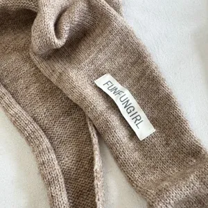 Close-up detail of the solid color knitted triangle scarf, showing soft texture and label.