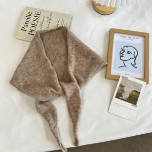 Detail view of a stylish brown knitted triangular scarf, cozy neck warmer for autumn and winter.
