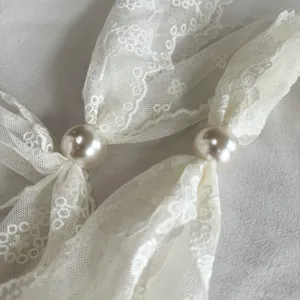 Exquisite white lace neckerchief detail featuring elegant faux pearl accents, delicate and chic.