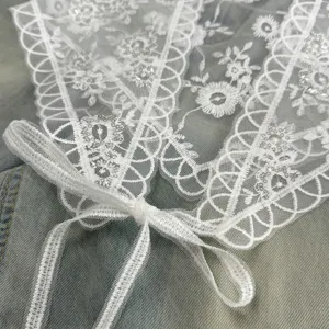 Detailed close-up view of elegant white lace triangle scarf with exquisite embroidery and ribbons.