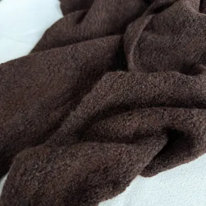 Vue détail du tissu d'écharpe en tricot marron foncé, accessoire d'hiver texturé doux.