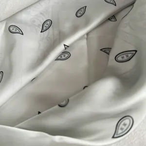 White silk scarf detail shot featuring unique teardrop print pattern, silky texture and soft fabric.