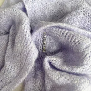 Gros plan d'un foulard triangulaire tricoté en violet clair doux avec motif cœur.