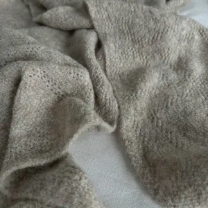 Gros plan détaillé d'une écharpe en tricot beige confortable, texture douce pour automne hiver.