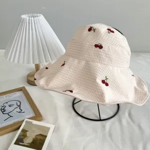Charming pink gingham bucket hat featuring cute embroidered cherries for sunny days.