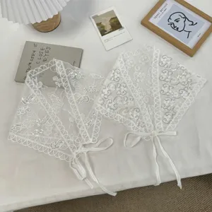 Detailed close-up of white lace sequin triangle scarf with delicate floral embroidery and ties.