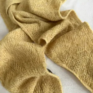 Détail de foulard triangulaire en tricot jaune, accessoire automne hiver pour femme.