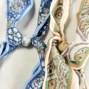 Primer plano detallado de largas cintas de seda con estampados florales, paisley y cuentas.