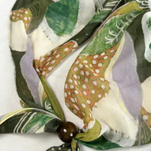 Close-up of a women's silk beaded scarf with artistic print, thin and elegant summer accessory.