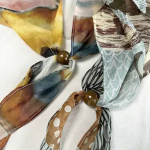 Detailed view of women's spring summer thin artistic print silk scarf with stylish beads.