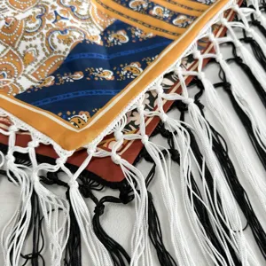 Close-up detail of ethnic style retro printed triangular scarf with black and white fringe.