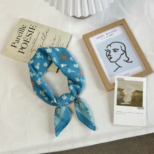 Detailed view of a blue floral cotton bandana scarf, featuring delicate white flowers and paisley.