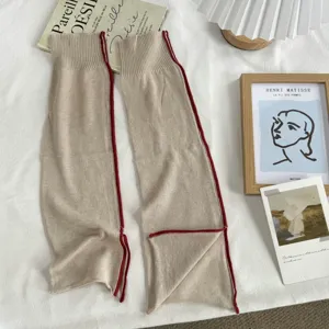 Minimalist beige knit leg warmers detail view showing exquisite red split edge design.
