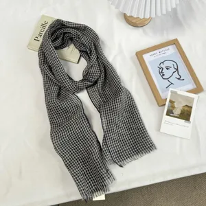 Gros plan détaillé sur le motif à carreaux classique et les franges du foulard doux.