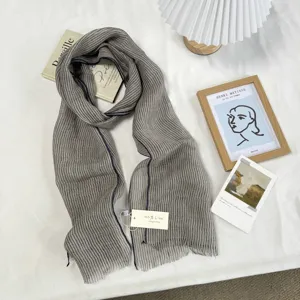 Gros plan sur la texture élégante de l'écharpe en lin rayé gris, tissu doux et respirant détail.