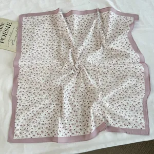 Detail shot of floral cotton square scarf, soft pink border and paisley pattern, elegant style.
