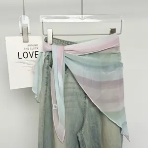 Sciarpa in seta a righe pastello da donna legata in vita con jeans per un look alla moda.