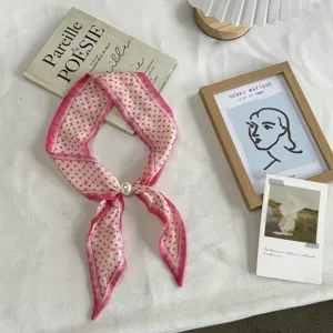 Detailed view of a chic pink polka dot slim silk scarf featuring an elegant faux pearl ring.