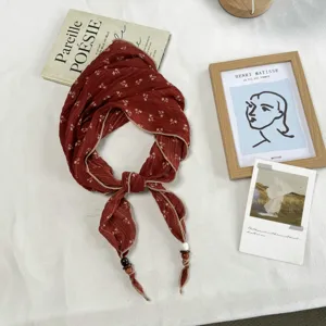 Detailed view of red floral pleated triangle scarf with cute wooden bead ends for spring styling.