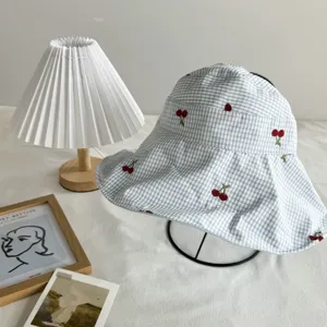Blue gingham bucket hat featuring cute red cherry embroidery, perfect for sun protection and daily style.