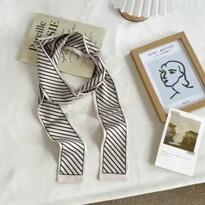Gros plan d'un foulard étroit à rayures chic dans un décor esthétique et chaleureux.