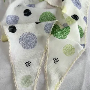Close-up of women's triangular scarf with crochet lace and colorful dot print details.
