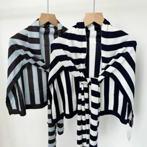 Detailed view of knitted striped shawls hanging on wooden hangers, perfect for summer air conditioning.