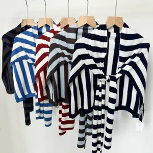 Detailed view of striped knitted shawl hanging on wooden hanger, cozy fabric, multi-color.