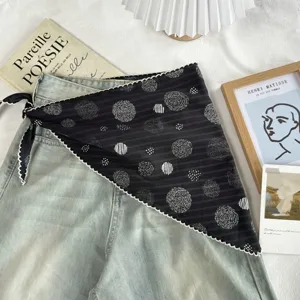 Detail view of black polka dot triangle scarf with lace trim and artistic flat lay props