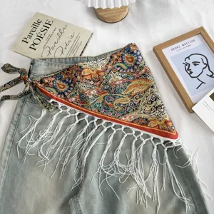 Detailed shot of ethnic retro printed triangle scarf with white fringe and waist tie strings.