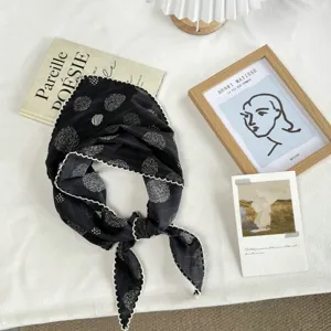 Detail view of the black floral patterned triangular headscarf with cute scalloped white lace edge.