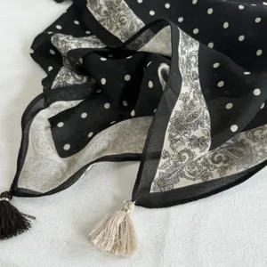 Detail view of a black and white polka dot paisley square scarf with elegant corner tassels.