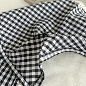 Detail van zwart-wit Gingham stof met klassiek geruit patroon en delicate kanten rand afwerking.
